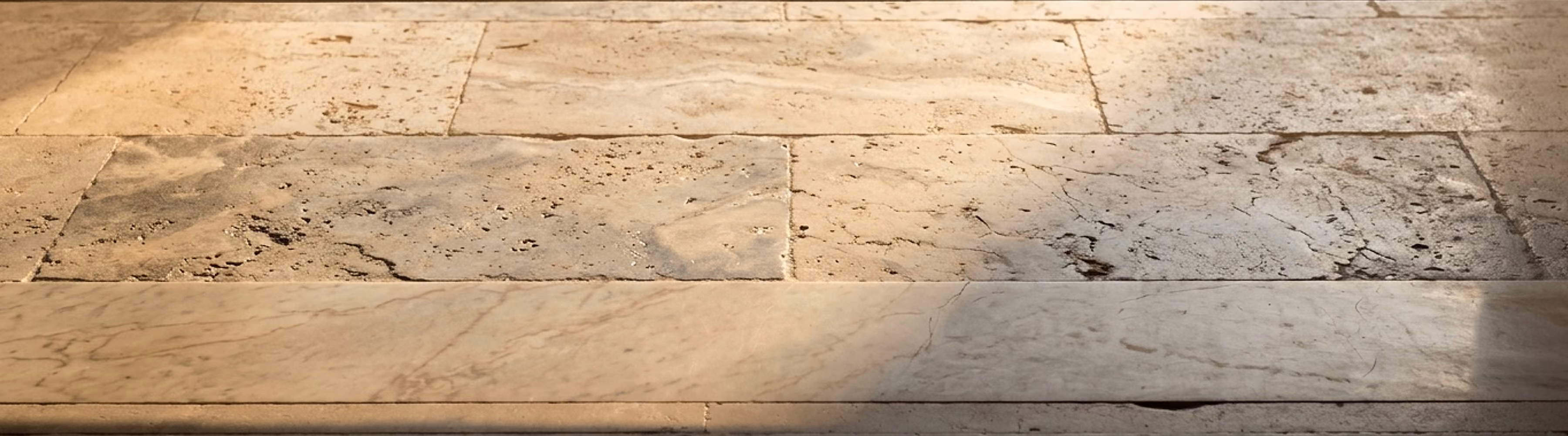 Raking sunrise light across an original travertine floor and marble threshold, revealing the patina of decades of use.
